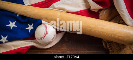 Un vecchio, antichi bandiera americana con vintage attrezzatura da baseball su una panca in legno Foto Stock