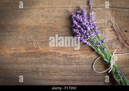 Lavanda in un mazzetto legato con una corda su un rustico sfondo legno Foto Stock