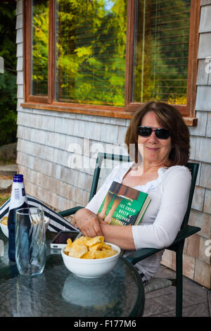 Donna di relax con un buon libro e uno snack Foto Stock