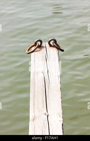 Anelli di ferro sulla parte superiore di una trave di legno per legare le barche ad esso Foto Stock