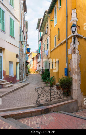 Strada stretta intersezione con colorati edifici vecchi e verde di piante in vaso nella città medievale di Villefranche-sur-Mer in francese R Foto Stock