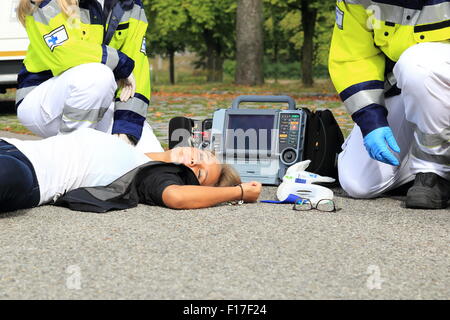 Una donna dopo un incidente con personale paramedico e del defibrillatore First Aid Foto Stock