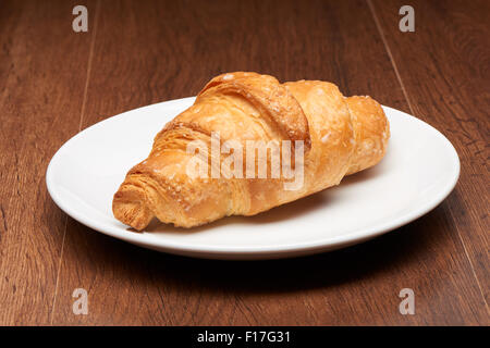 Freschi croissant francesi su bianco piastra ceramica su legno scuro dello sfondo della tabella Foto Stock