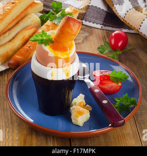 Uovo sodo per la prima colazione è servita con pane bastoni su un tavolo di legno. Foto Stock