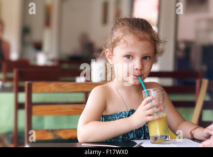 Carino piccolo kid ragazza di bere succo di frutta in cafe con sguardo serio Foto Stock