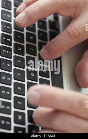 Primo piano di un uomo digitando su una tastiera portatile Foto Stock