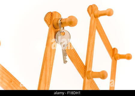 Chiave di casa appesa al gancio di legno isolato su bianco Foto Stock