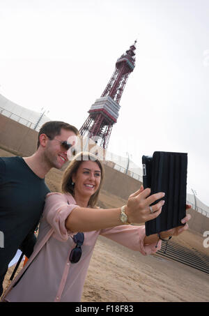 Blackpool, Regno Unito. Il 30 agosto, 2015. Louise Logan da Blackpool e Nick argilla da Manchester sono stati per la prima volta nella linea di persone che partecipano a un tentativo di rompere il Guinness World Record per il più lungo Selfie Catena del relè che è stata fatta in Blackpool Lancashire. Merlin Entertainments & VisitBlackpool teamed in su per tentare di rompere l'attuale record mondiale che si erge a 531 selfies consecutivi. I visitatori e gli abitanti locali hanno la possibilità a testa in giù per la Commedia iconica tappeto di fronte la mitica Torre di Blackpool, a fare la storia e ottenere selfie snap-felice. Credito: Barrie Harwood/Alamy Live News Foto Stock