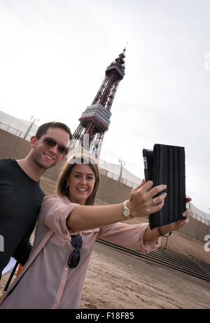 Blackpool, Regno Unito. Il 30 agosto, 2015. Louise Logan da Blackpool e Nick argilla da Manchester sono stati per la prima volta nella linea di persone che partecipano a un tentativo di rompere il Guinness World Record per il più lungo Selfie Catena del relè che è stata fatta in Blackpool Lancashire. Merlin Entertainments & VisitBlackpool teamed in su per tentare di rompere l'attuale record mondiale che si erge a 531 selfies consecutivi. I visitatori e gli abitanti locali hanno la possibilità a testa in giù per la Commedia iconica tappeto di fronte la mitica Torre di Blackpool, a fare la storia e ottenere selfie snap-felice. Credito: Barrie Harwood/Alamy Live News Foto Stock