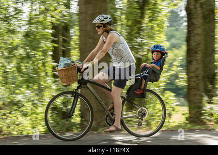 Signora escursioni in bicicletta con il bambino del vettore in campagna, England, Regno Unito Foto Stock