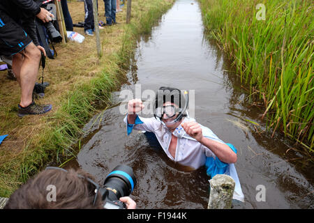 Mondo Bog Snorkelling campionati, Llanwrtyd Wells, Powys, Wales, Regno Unito. Il 30 agosto, 2015. Concorrente Steven prati vestito come Elvis completa il suo snorkeling a questo anni 30th World Bog Snorkelling campionato che si terrà in due riempito di acqua paludosa di trincee nel Galles centrale. I concorrenti devono fare snorkel 120 yard in totale. Foto Stock