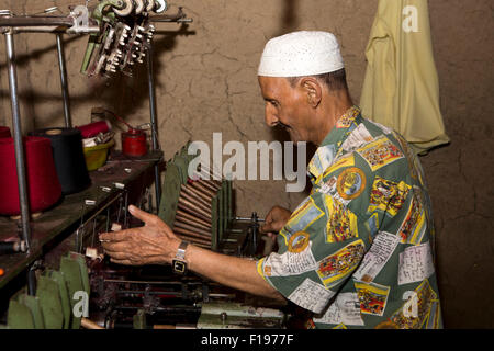 India, Jammu e Kashmir Srinagar, produzione pashmina, uomo pasminas tessitura su telaio meccanico in officina scuro Foto Stock