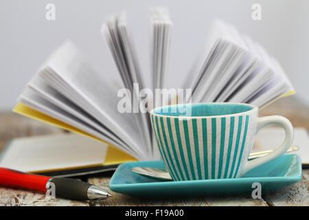 Tazza di caffè con il libro aperto in background Foto Stock