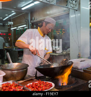 Cuoco prepara il cibo nel corso flaming wok al marciapiede stand alimentari nel Quartiere Musulmano di Xi'an, Cina Foto Stock