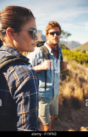 Giovane sulla passeggiata in campagna. La donna in piedi davanti guardando una vista con uomo in background. Coppia caucasica escursionismo in natu Foto Stock