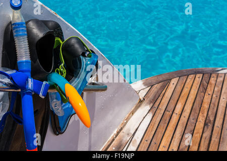 Nella foto la barca con una curva ponte di legno bagnato,sulla sinistra le pinne, maschera,scuba di gomma per lo snorkeling e nell'oceano di sfondo Foto Stock