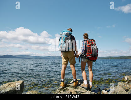 Vista posteriore di affettuosa escursionisti ammirando il mare Foto Stock