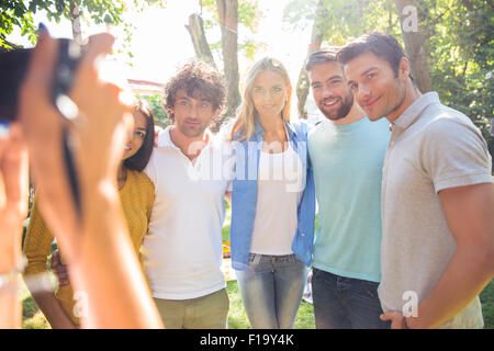 Mani femminili tenendo la fotocamera digitale e fare foto di un felice gruppo amici Foto Stock