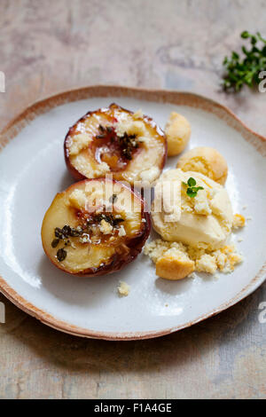 Pesche al forno con timo, gelati e amaretti Foto Stock