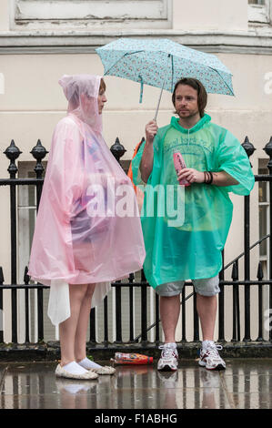 Londra, Regno Unito. Il 31 agosto 2015. Un paio di ponchos rifugiarsi come heavy rain non smorzare gli spiriti di coloro che prendono parte a due giorno di carnevale di Notting Hill a ovest di Londra. Credito: Stephen Chung / Alamy Live News Foto Stock