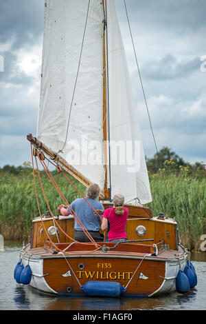 Un giovane vela una Norfolk Broads barca a vela verso il basso attraverso una delle dighe in modo da Potter Higham a Hickling ampia. Foto Stock