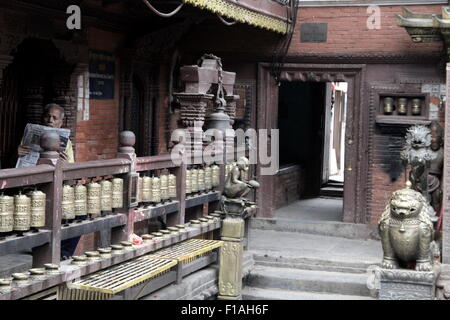 Uomo Legge giornale all'interno del tempio d'oro di Kathmandu Foto Stock