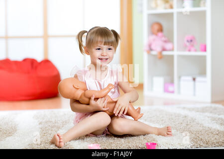 Carino bambina holding e abbracciando la bambola Foto Stock