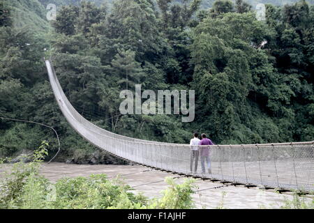 Due uomini a piedi attraverso la passerella attraversando il fiume Trishuli in Kurintar, Napal Foto Stock