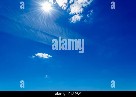 Bright sole che splende nel cielo blu con nuvole sul giorno di estate Foto Stock