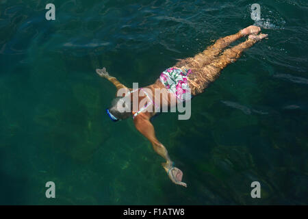 Elevato angolo di visione della donna senior che nuotare con gli occhiali di protezione sotto verde acqua del mare. Foto Stock