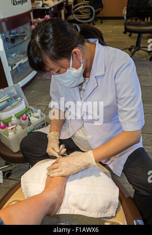 Vietnamese-American, donna adulta, pedicurist, rimuovendo le cuticole, pedicure, manicure, Novato, Marin County, California Foto Stock