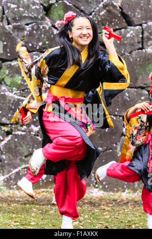 Kumamoto, Giappone, Yosakoi Festival. Corpo di ballo di bambini, 10-16 anni, tenendo naruko e in nero happi coats, ballare nella parte anteriore del muro di castello. Foto Stock