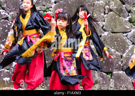 Kumamoto, Giappone, Yosakoi Festival. Corpo di ballo di bambini, 10-16 anni, tenendo naruko e in nero happi coats, ballare nella parte anteriore del muro di castello. Foto Stock