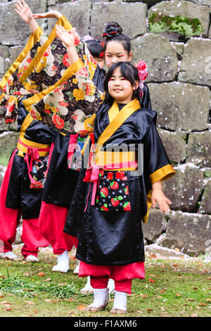 Kumamoto, Giappone, Yosakoi Festival. Corpo di ballo di bambini, 10-16 anni, tenendo naruko e in nero happi coats, ballare nella parte anteriore del muro di castello Foto Stock