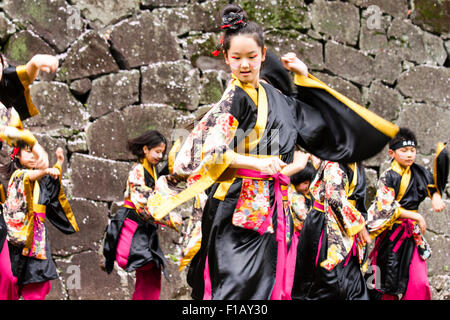 Kumamoto, Giappone, Yosakoi Festival. Corpo di ballo di bambini, 10-16 anni, tenendo naruko e in nero happi coats, ballare nella parte anteriore del muro di castello Foto Stock