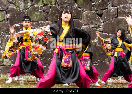 Kumamoto, Giappone, Yosakoi Festival. Corpo di ballo di bambini, 10-16 anni, tenendo naruko e in nero happi coats, ballare nella parte anteriore del muro di castello Foto Stock