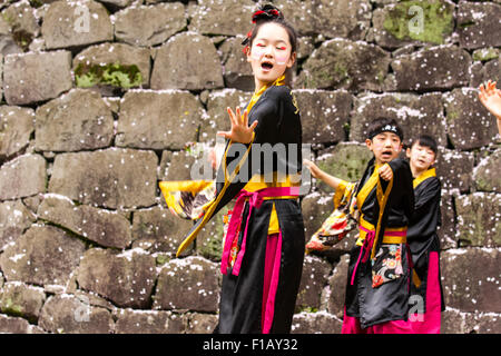 Kumamoto, Giappone, Yosakoi Festival. Corpo di ballo di bambini, 10-16 anni, tenendo naruko e in nero happi coats, ballare nella parte anteriore del muro di castello Foto Stock