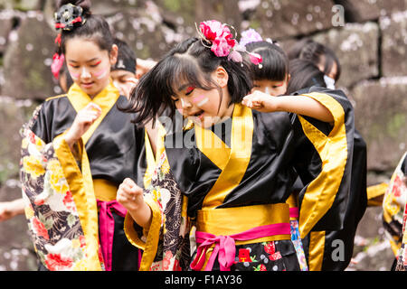 Kumamoto, Giappone, Yosakoi Festival. Corpo di ballo di bambini, 10-16 anni, tenendo naruko e in nero happi coats, ballare nella parte anteriore del muro di castello Foto Stock