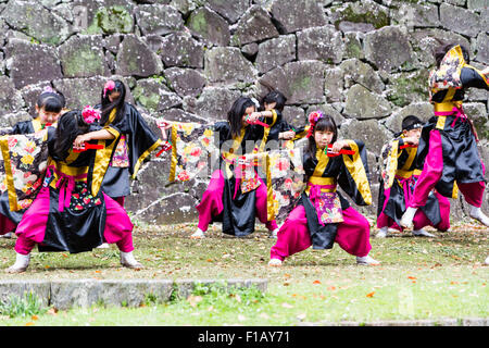 Kumamoto, Giappone, Yosakoi Festival. Corpo di ballo di bambini, 10-16 anni, tenendo naruko e in nero happi coats, ballare nella parte anteriore del muro di castello. Foto Stock