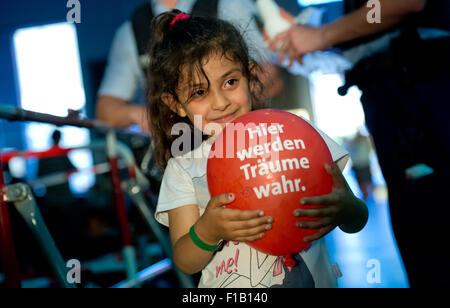 Una piccola ragazza di rifugiati dalla Siria detiene un palloncino rosso che indica 'risme si avvera qui' ('Hier werden wahr Traeume') a Monaco di Baviera la stazione ferroviaria centrale di Monaco di Baviera, Germania, il 31 agosto 2015. Molti rifugiati dell Afghanistan, alla Siria e al Pakistan, arrivati in treno da Budapest, la polizia ha accolto i profughi e li guidò a una sala di registrazione nelle vicinanze. Foto: Sven Hoppe/dpa Foto Stock