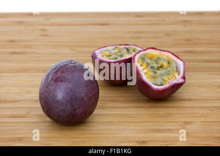 Close-up di un insieme e dividere i frutti della passione (granadiglie, viola granadilla (Passiflora edulis)) su una tavola di legno. Foto Stock