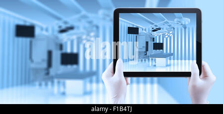 Mano utilizzando computer tablet mostrare le apparecchiature e i dispositivi medici in una moderna sala operatoria Foto Stock