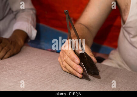 India, Jammu e Kashmir Srinagar, Città Vecchia, produzione Pashmina, mani di man picking pillole e peli off panno con utensile di metallo Foto Stock