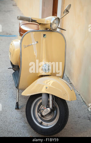 Gaeta, Italia - 19 agosto 2015: Classico giallo scooter Vespa parcheggiata sorge in prossimità della parete verticale della foto Foto Stock