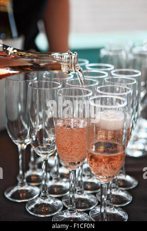 Champagne rosato che viene versato in bicchieri di champagne Foto Stock