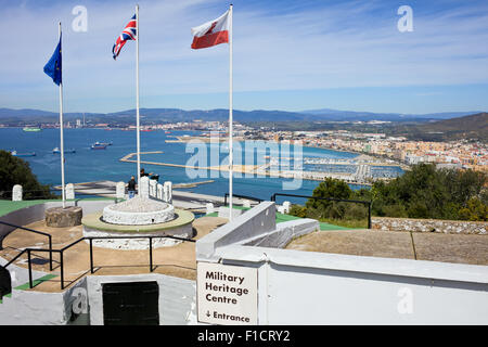 Patrimonio militare centro sulla Roccia di Gibilterra con le bandiere della Unione europea, Regno Unito e Gibilterra, la baia e la città di La Linea città in Spagna Foto Stock