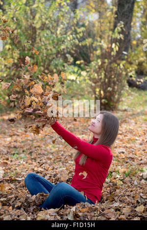 Felice ragazza che gioca con il colore giallo Foglie di autunno nel parco Foto Stock