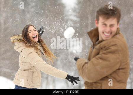 Giovane giocando con la neve e la fidanzata di gettare una palla in vacanze invernali Foto Stock