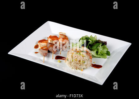 Menu di kebab con riso e verdure in piatto bianco su sfondo nero Foto Stock