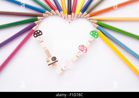 Crayon cuore - forma di cuore fatta di matite colorate e legante clip su sfondo bianco Foto Stock
